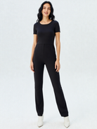 Woman wearing a black breastfeeding friendly jumpsuit on a white background
